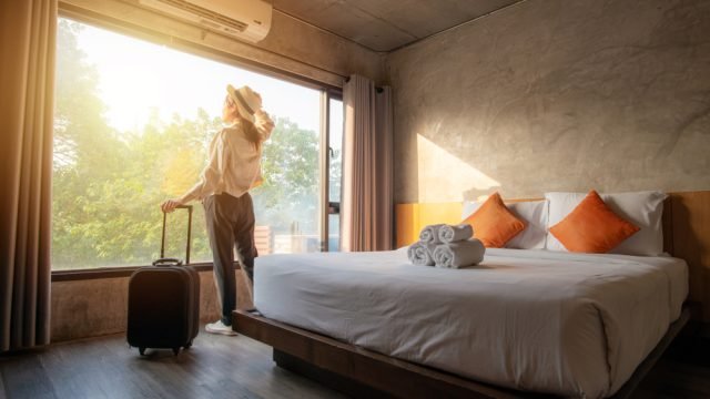 a lady standing in her hotel room after arrival showing the concept of hygienic hotel room 